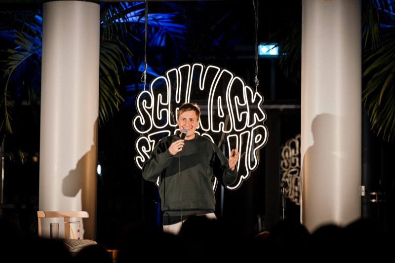 Comedian vor dem SCHNACK Stand-Up Neonschild